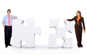 business partnership of a couple of businesspeople leaning on puzzle pieces isolated over a white background